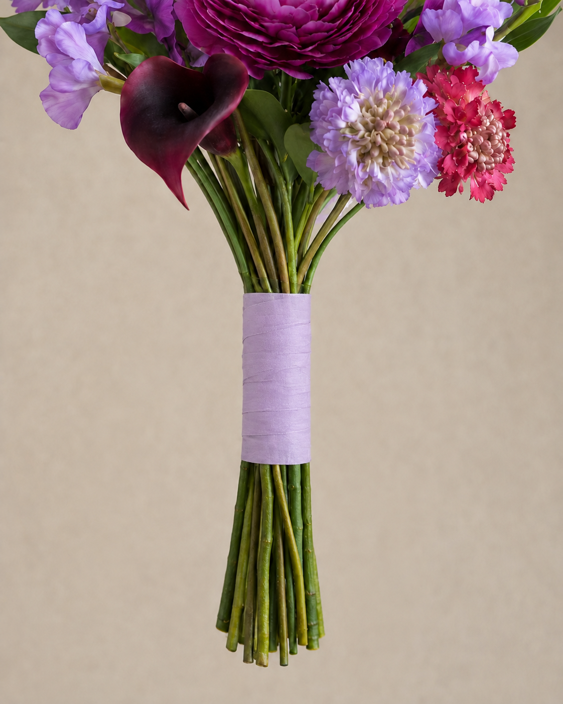 Close-up of the Jewel Peony Posy bouquet stems bound with lavender organza ribbon, showing the wrapped base and finished construction detail