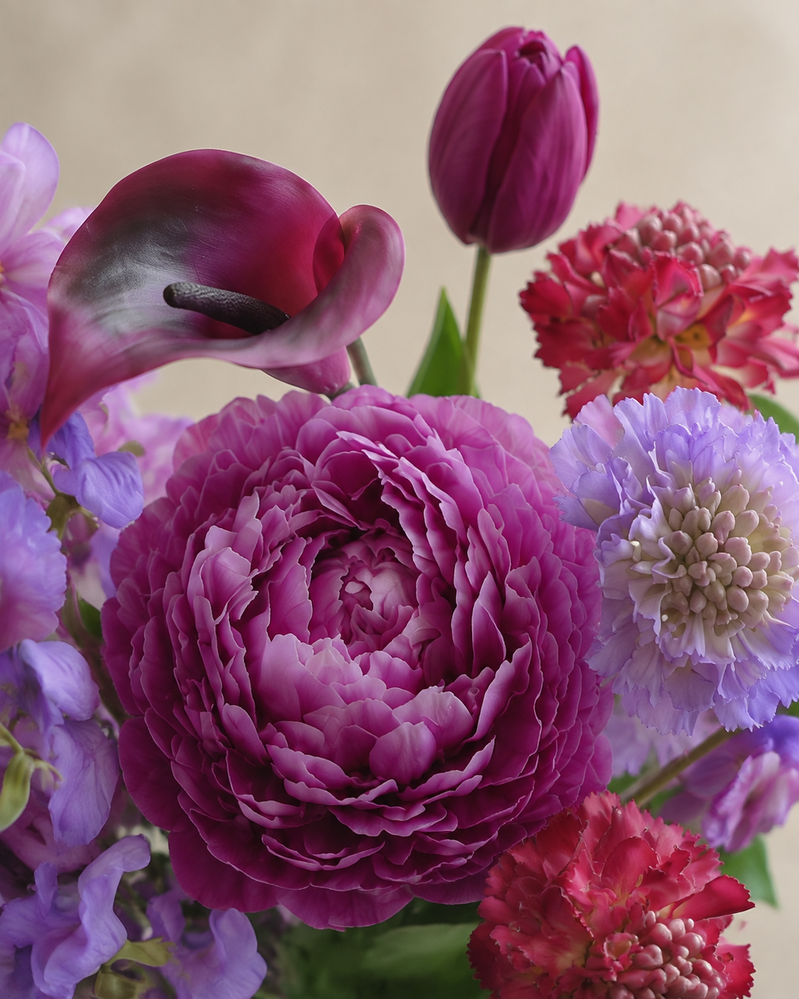 Macro close-up of the Jewel Peony Posy bouquet showing the magenta peony/ranunculus center, dark burgundy calla lily, purple scabiosa and red dianthus