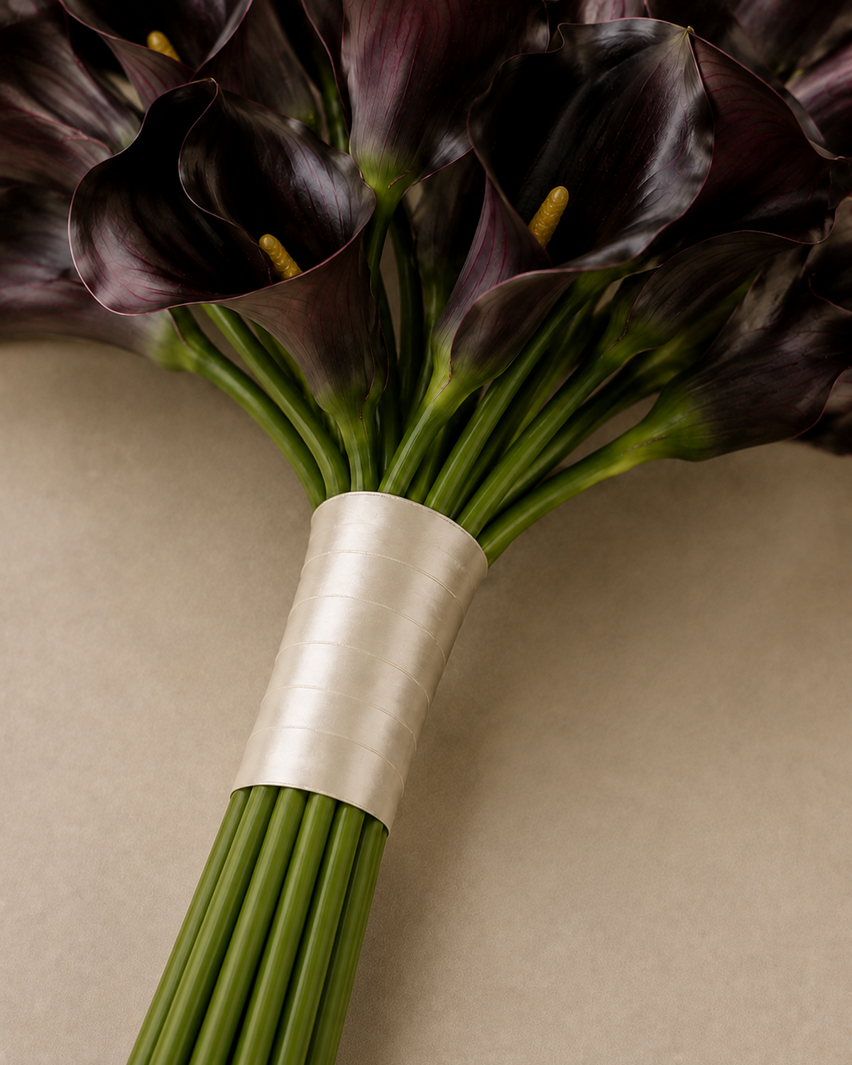 Macro close-up of black calla lily petals and ribbon-wrapped stems, texture detail