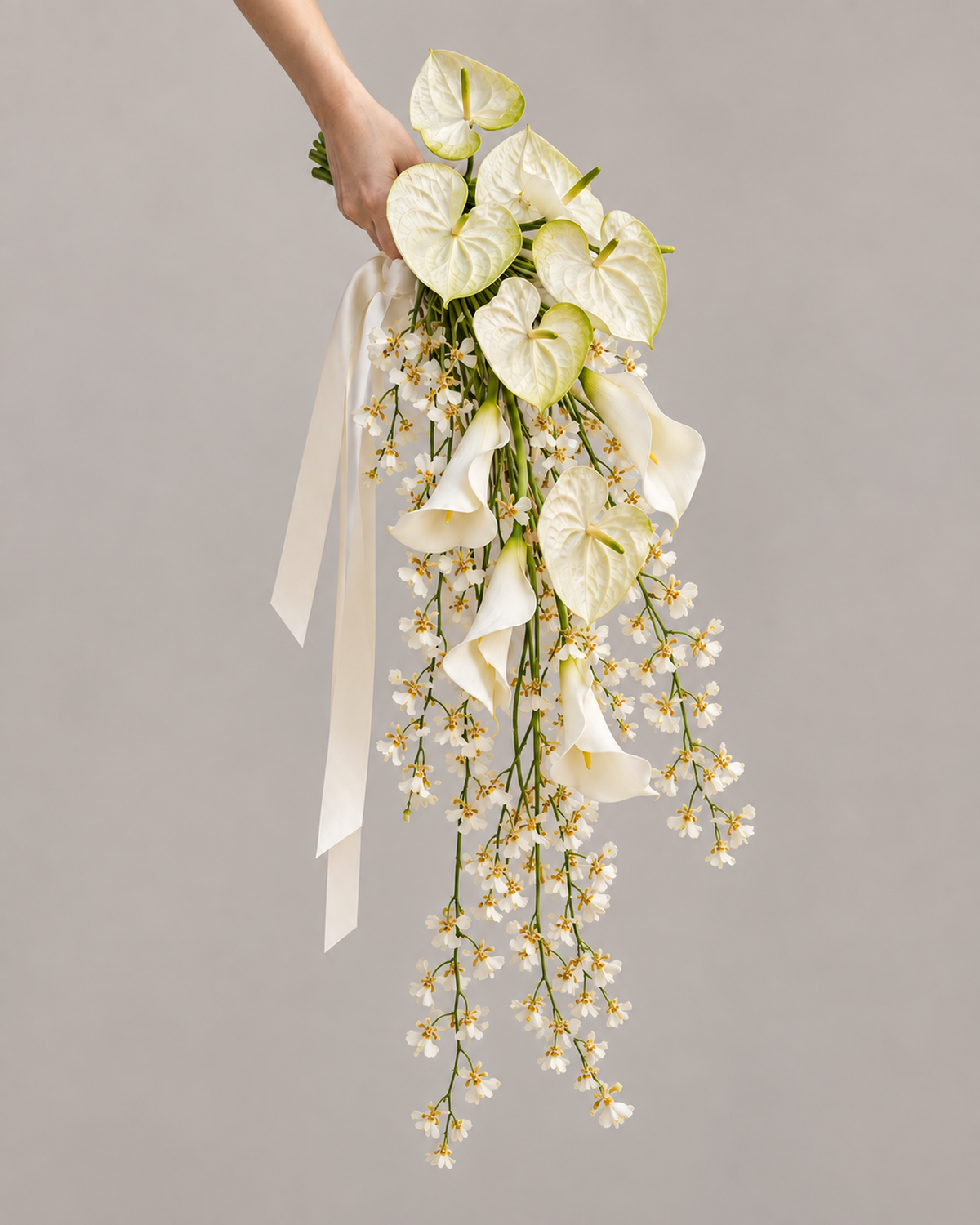 Full studio shot of the White Oncidium Cascade bridal bouquet showing white anthurium, calla lily and cascading Oncidium orchid stems.