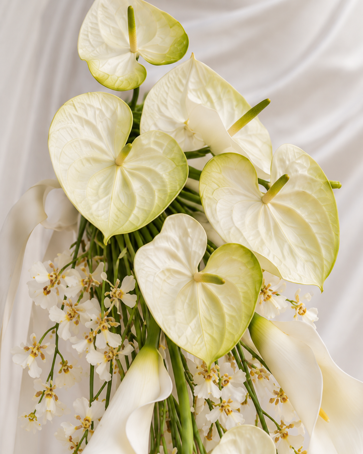 Close-up of the white anthurium and calla lily blooms at the top of the White Oncidium Cascade bridal bouquet.